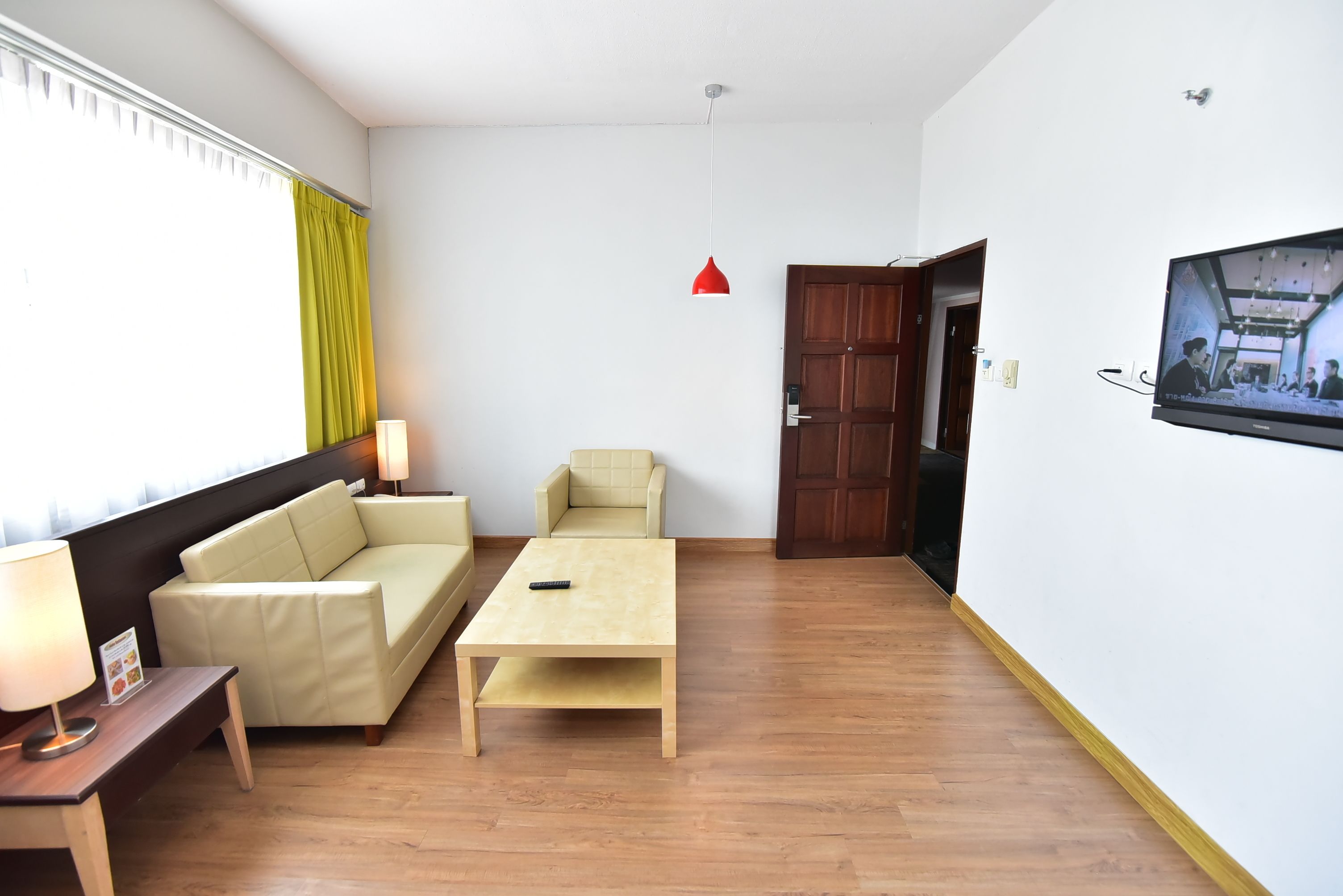 Una sala de estar con un sofá, una mesa de centro, un televisor y piso de madera.