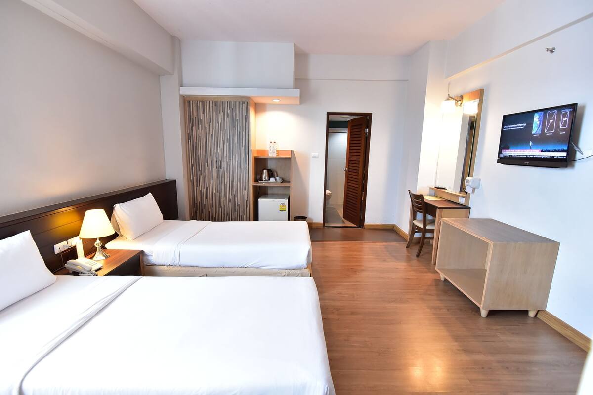 A hotel room with two beds, a TV, a desk, and a wardrobe.