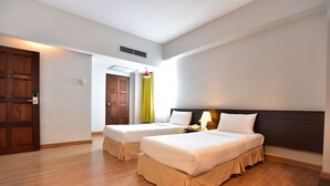 Habitación de hotel con dos camas, suelo de madera, cabecera oscura y ventana con cortinas.