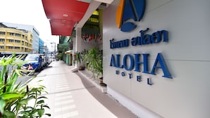 El exterior del Hotel Aloha, con un letrero llamativo y un corredor cubierto.