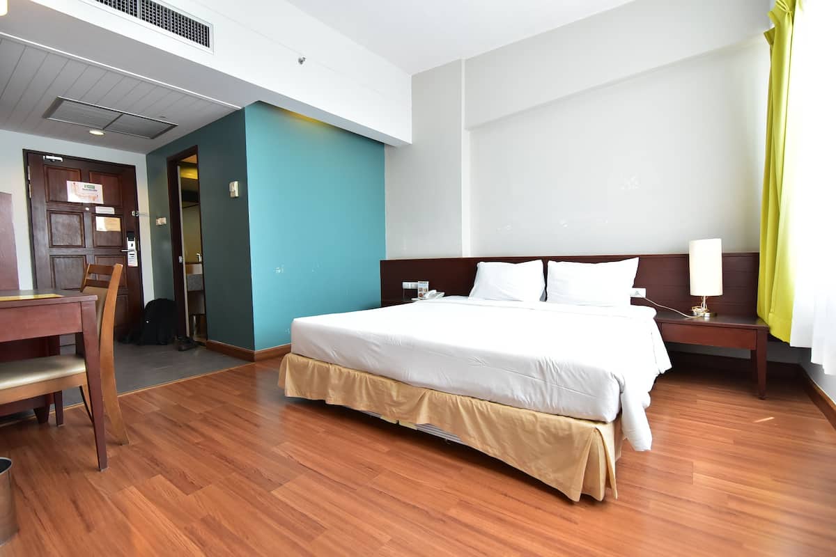 A hotel room with a large bed, a desk, and a chair.