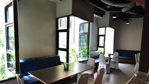 Un restaurante con una mesa de madera, sillas blancas y un banco azul.