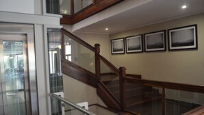 Un escalier en bois avec des rampes en verre, menant à l’étage supérieur.
