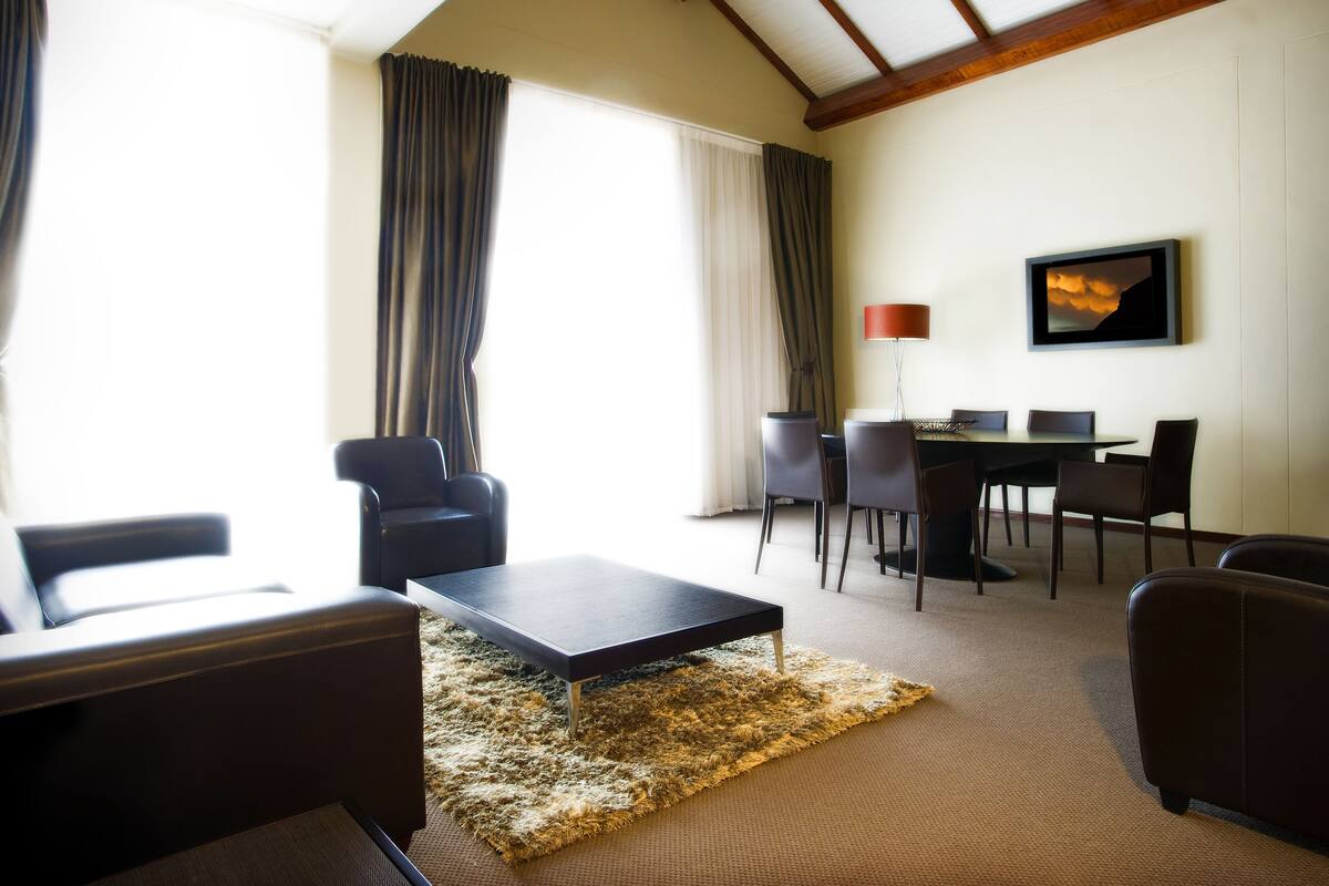 Een moderne woonkamer met een bank, een salontafel en een eethoek met stoelen en een tafel.