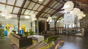 Un hall d’entrée spacieux avec un plafond haut, un mobilier moderne et un grand mur de verre.