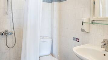 A bathroom with a shower, toilet, sink, and a glass shelf.