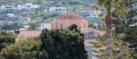 A coastal town with white buildings, a prominent church with a red-tiled roof, and lush greenery.