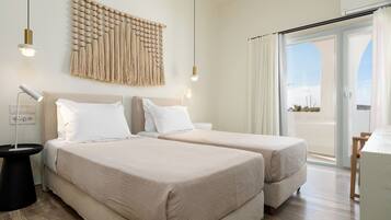 A hotel room with two beds, a wall tapestry, pendant lights, and a view of the outdoors.