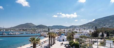 A coastal town with a marina, white buildings, palm trees, and a clear blue sky.