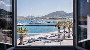 A marina with boats, a road with cars, and a mountain in the background. - Hotel Oasis (Paros)