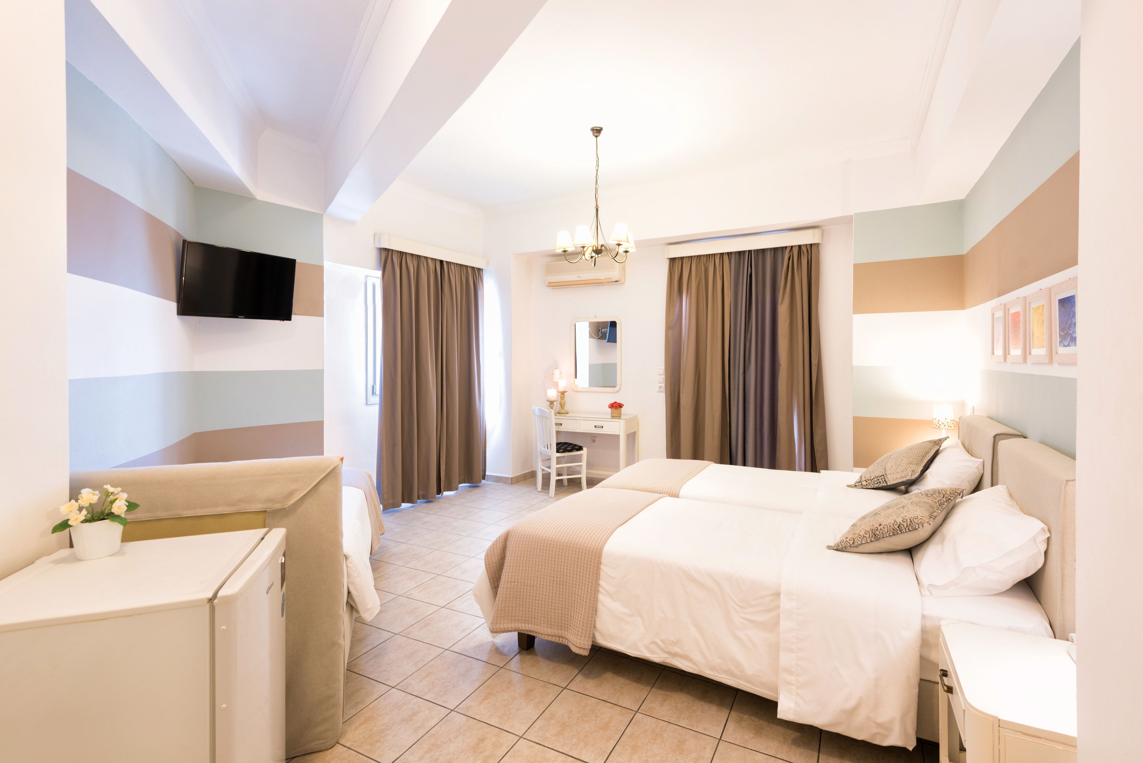 Une chambre d’hôtel équipée d’un lit, d’un bureau, d’une chaise, d’une télévision et d’un petit réfrigérateur.
