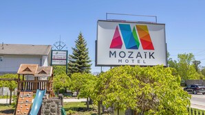 A motel sign with a colorful logo and the name 'MOZAÏK MOTEL'.