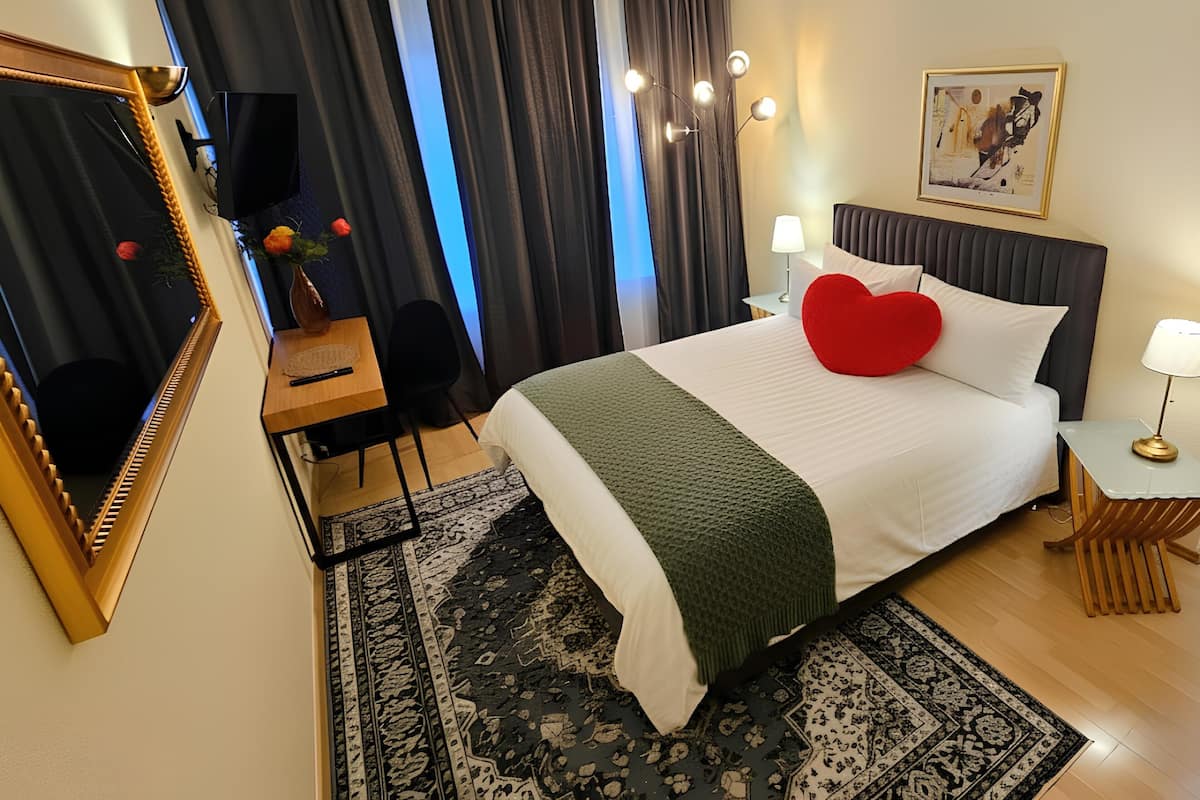 Een hotelkamer met een bed, een bureau, een stoel, een spiegel, een lamp en een schilderij aan de muur.