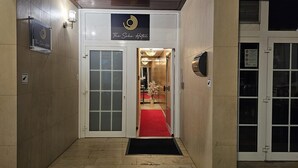 Een hotelingang met een rode loper die leidt naar een receptie.