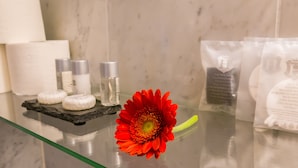Een badkamermeubel met toiletartikelen, een rode bloem en een handdoek.