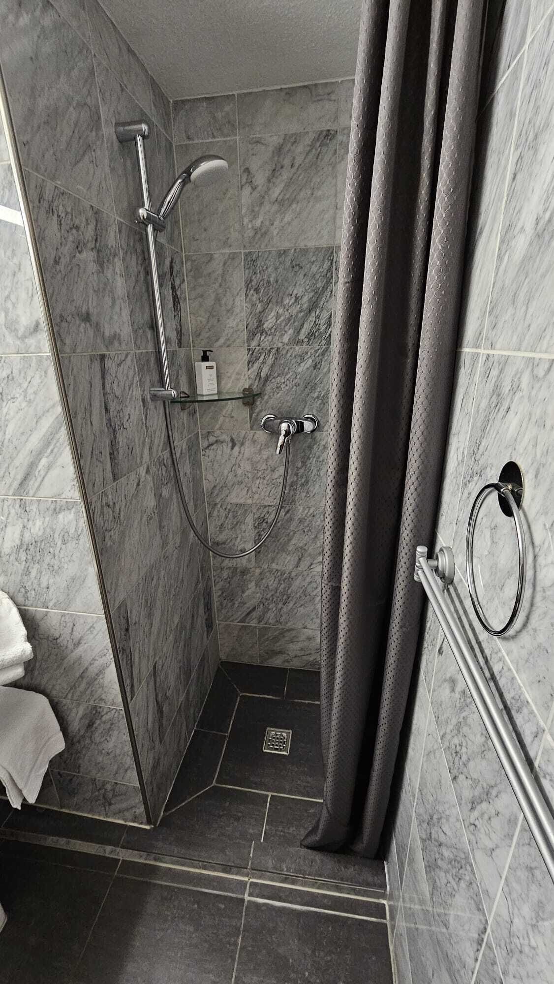 Ein modernes Badezimmer mit Dusche, Marmorfliesen und einem Handtuchhalter.