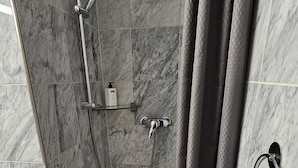 Een moderne badkamer met een douche, marmeren tegels en een handdoekhouder.