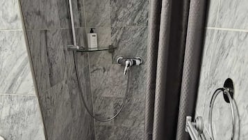 Ein modernes Badezimmer mit Dusche, Marmorfliesen und einem Handtuchhalter.