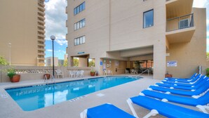 A swimming pool with blue lounge chairs and a no lifeguard sign. - The Dunes Towers by Palmetto Vacations (Myrtle Beach)