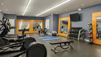 A modern gym with treadmills, exercise equipment, mirrors, and a TV.