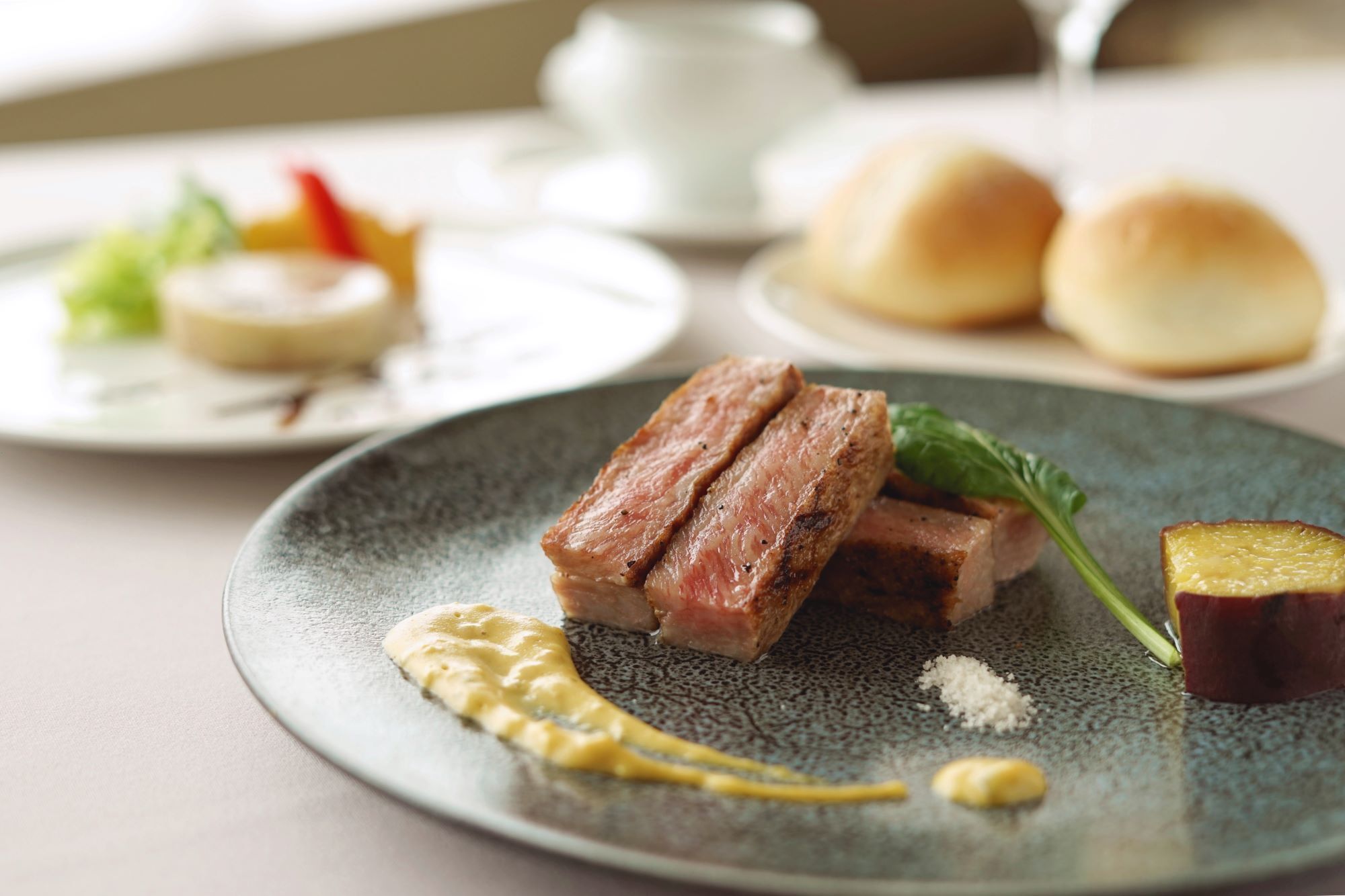 A plate with sliced meat, a garnish, and a side dish.
