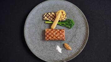 Un plato con carne a la parrilla, maíz, brócoli y un trozo pequeño de queso.