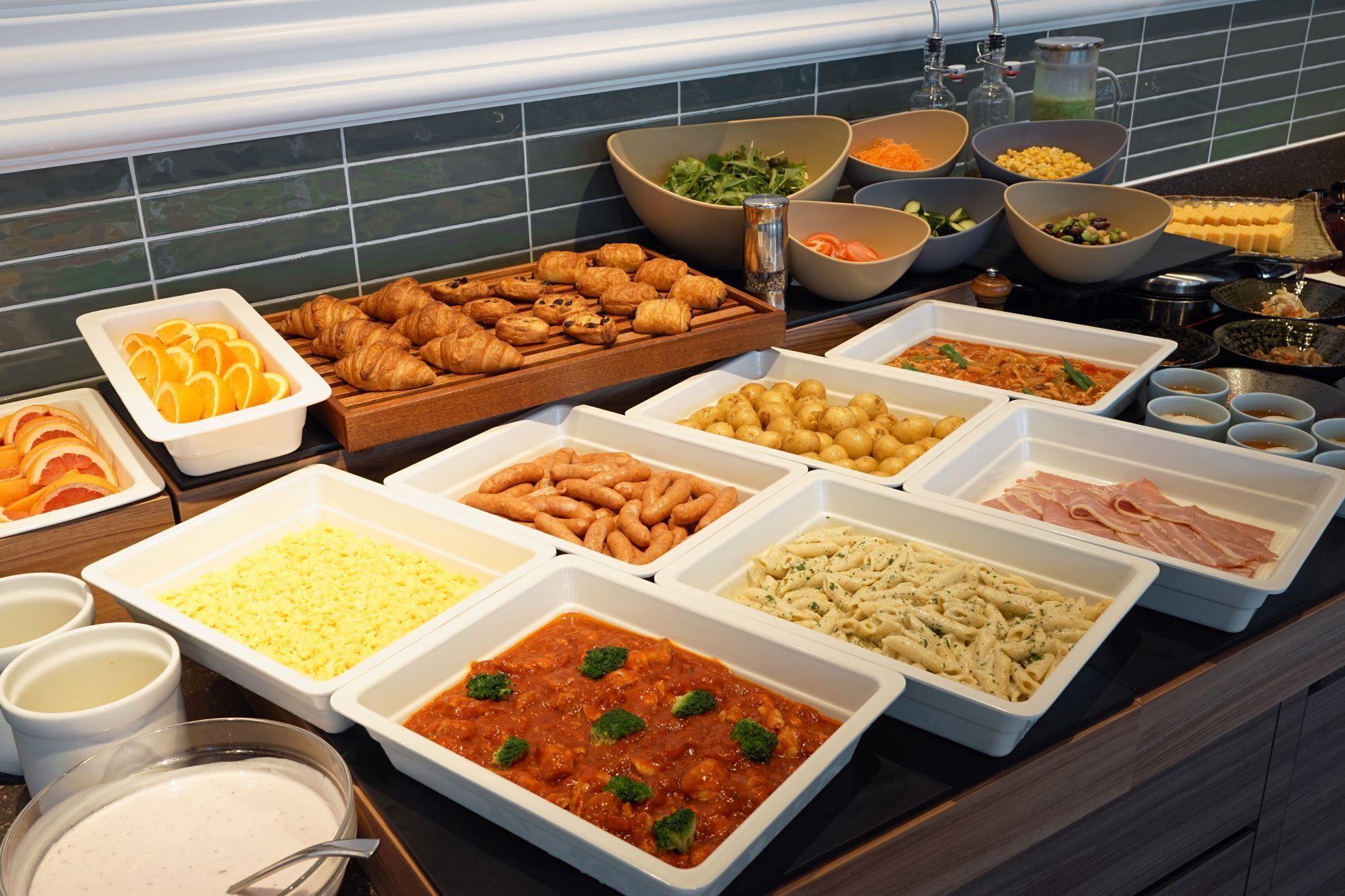 A buffet with various food items including pastries, salads, and pasta dishes.