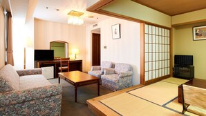 A traditional Japanese-style room with tatami flooring, a low table, a sofa, and a television. - Hotel Marroad Tsukuba (Tsuchiura)