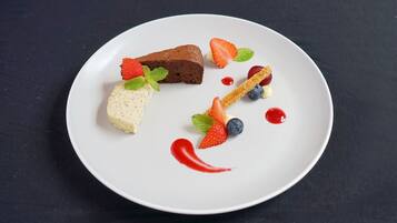 A dessert plate with a brownie, cheesecake, and fruit on a white plate.