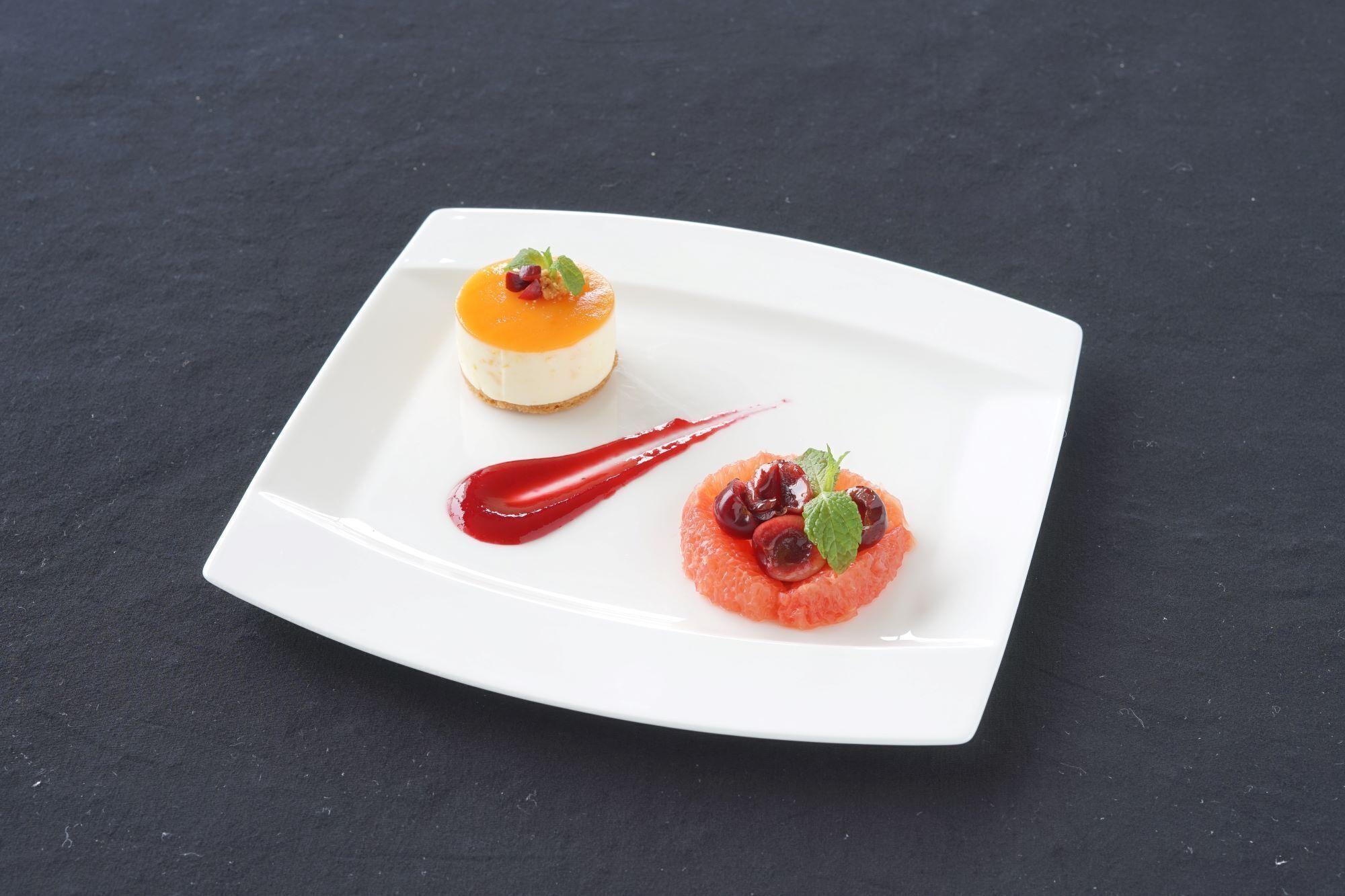 A white plate with two desserts on a dark surface.