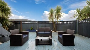 A patio with wicker furniture, a wooden table, and a view of the sky. - Wanderlust Inn (Ocean Shores)