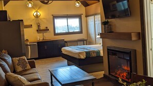 A cozy living room with a fireplace, wooden furniture, and a television mounted on the wall. - Wanderlust Inn (Ocean Shores)