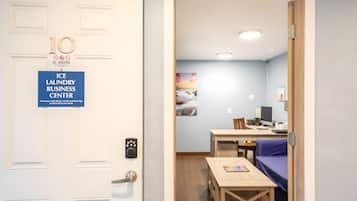 A hotel room with a door labeled "Ice Laundry Business Center" and a view into a room with a desk, chair, and a bed.