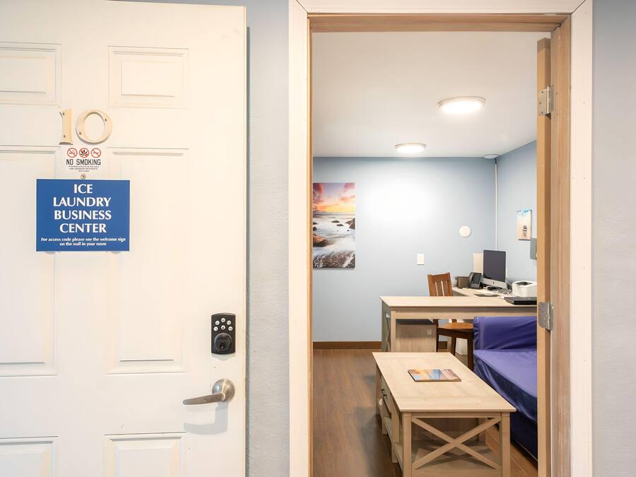 A hotel room with a door labeled "Ice Laundry Business Center" and a view into a room with a desk, chair, and a bed.