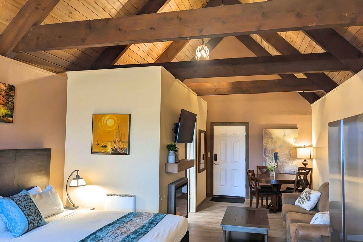 Una habitación acogedora con una cama, un escritorio, una silla y un sofá. Hay un cuadro en la pared y una lámpara sobre el escritorio.
