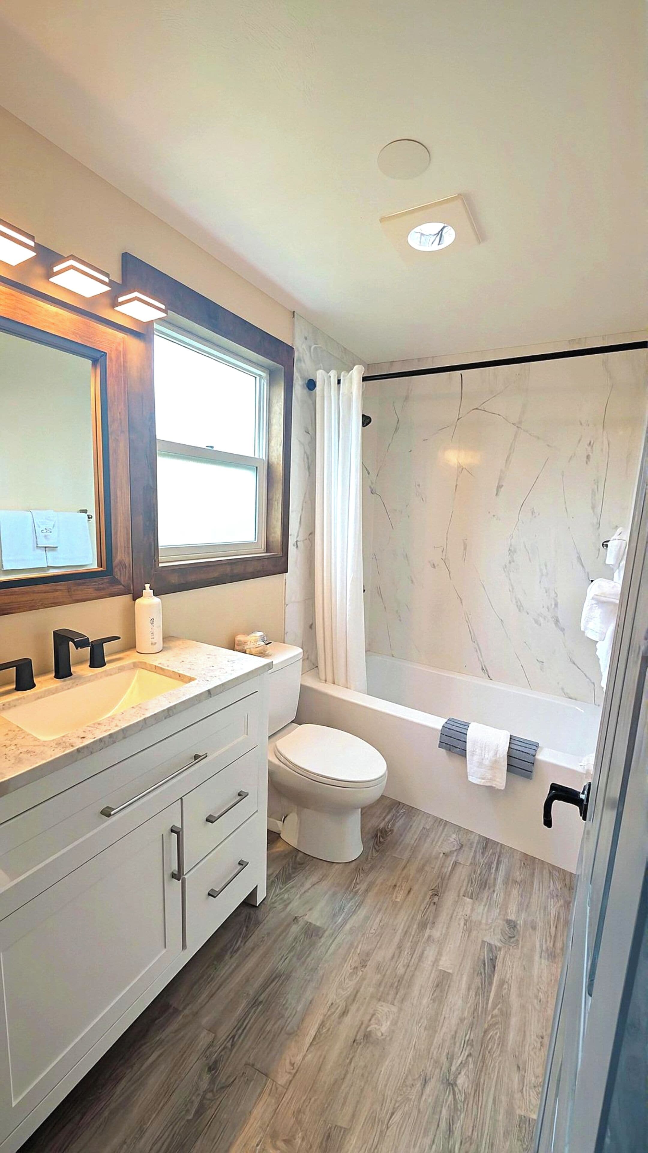 Une salle de bain moderne avec une douche en marbre, des toilettes, un lavabo avec un meuble-vasque et un grand miroir.