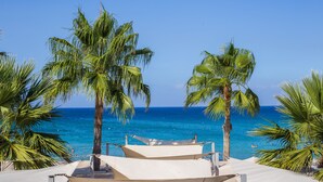 A beach view with palm trees and a clear sky. - Vrissaki Beach Hotel (Paralimni)