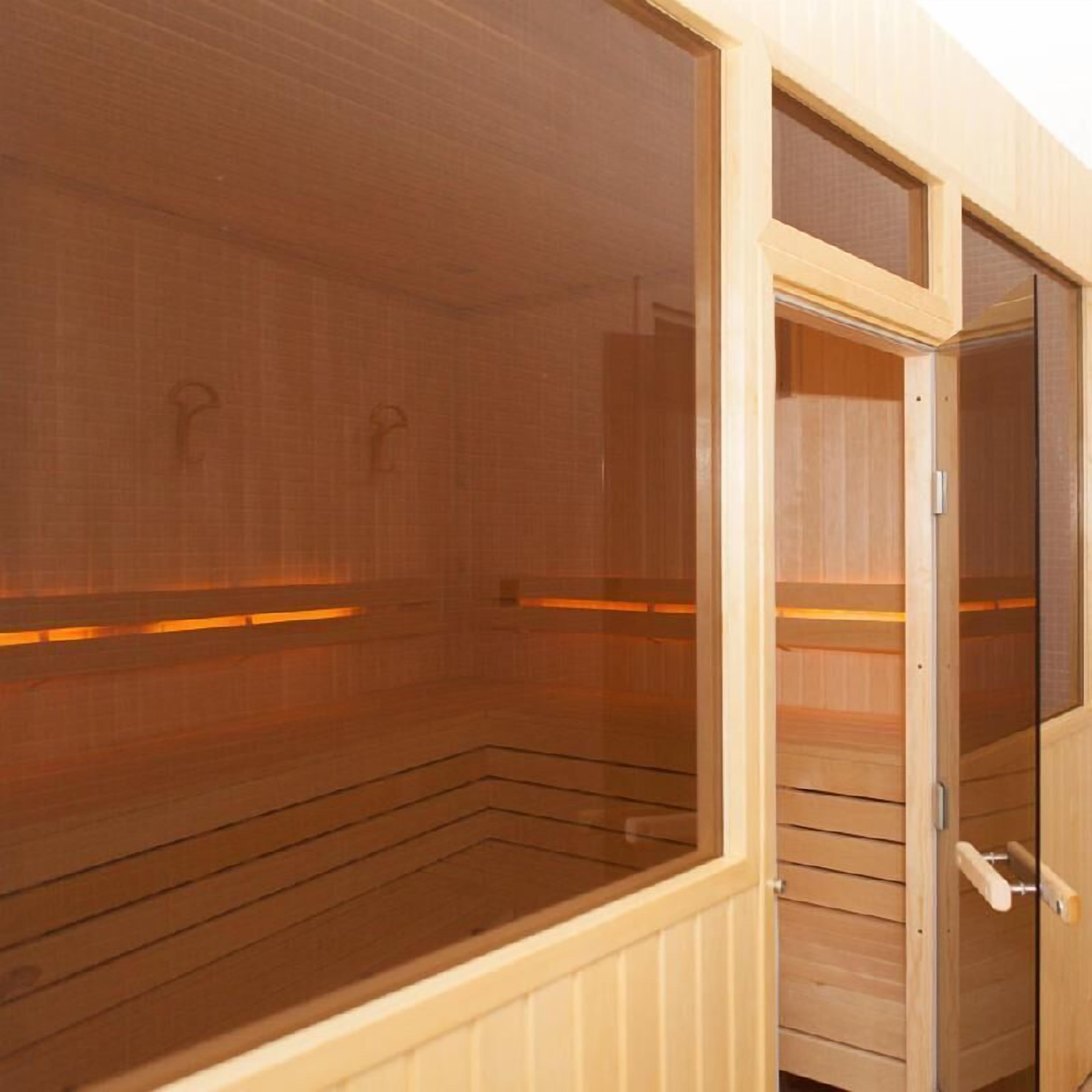 A sauna room with wooden walls and a glass door.