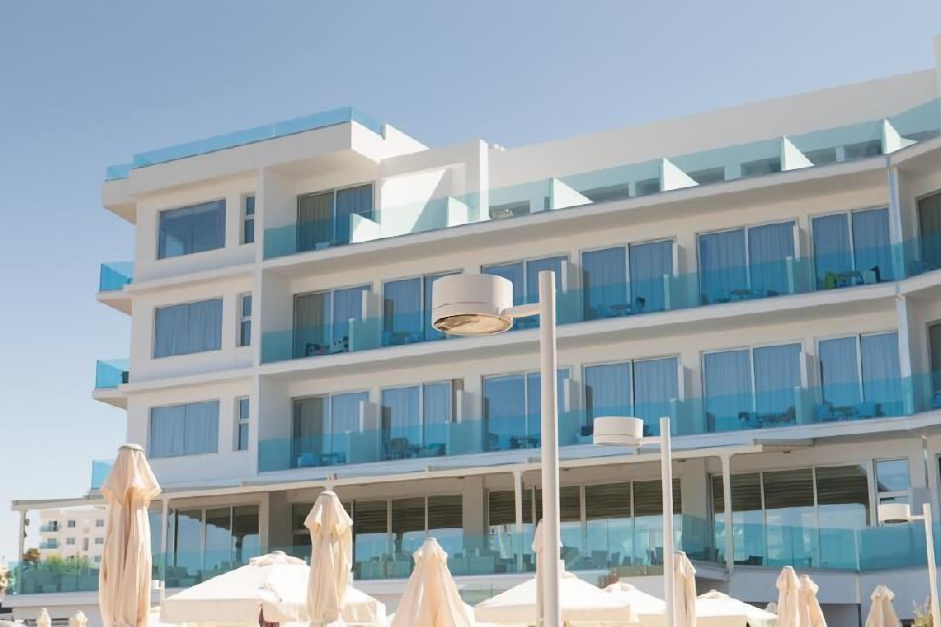 A modern hotel with multiple balconies, large windows, and outdoor seating areas.