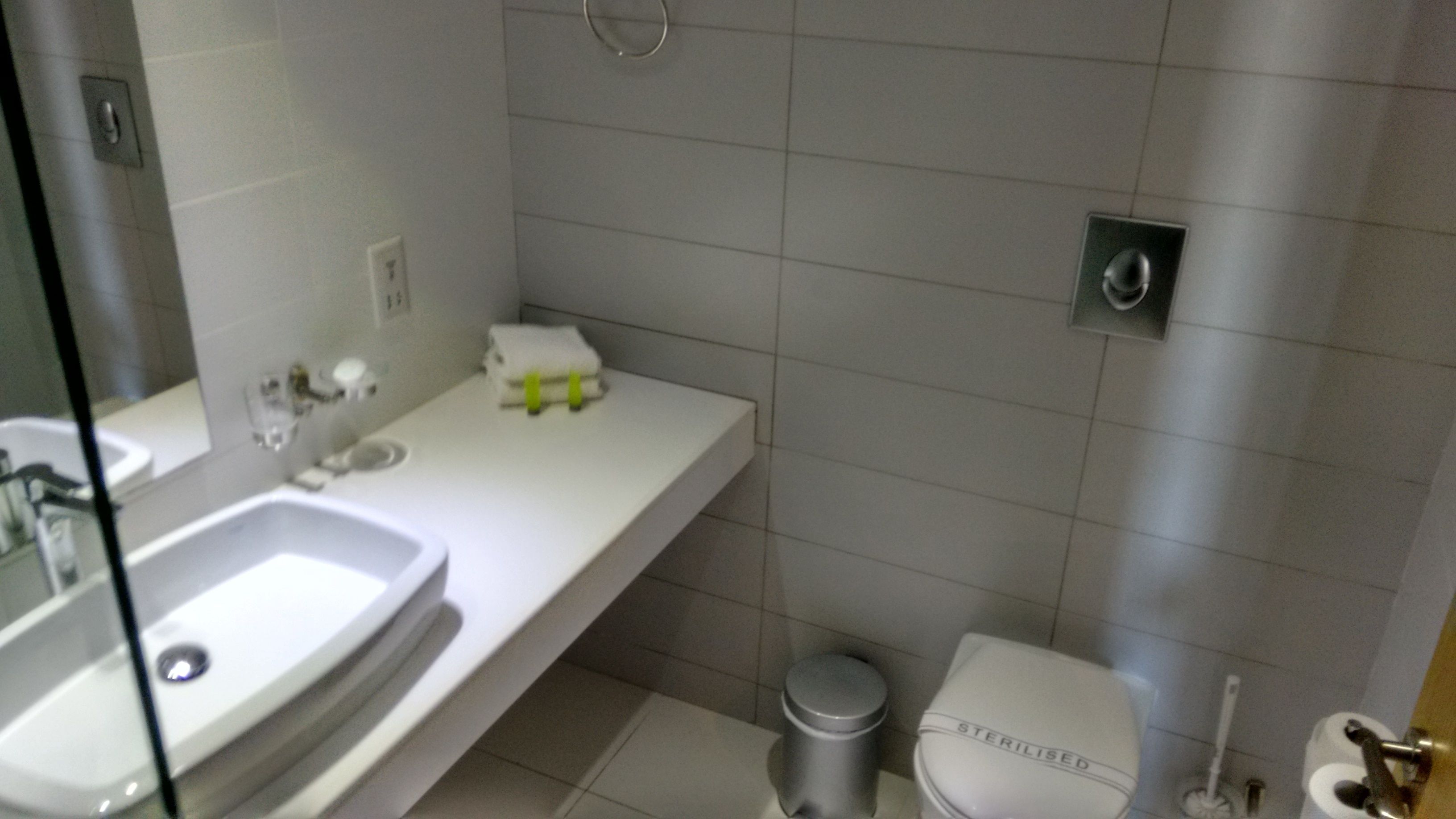 A modern bathroom with a white sink, mirror, and toilet.