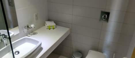 A modern bathroom with a white sink, mirror, and toilet.