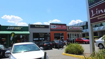 A parking lot with several cars, a Subway restaurant, Rustic Italian, PH MinH Long, and Nando's restaurants.