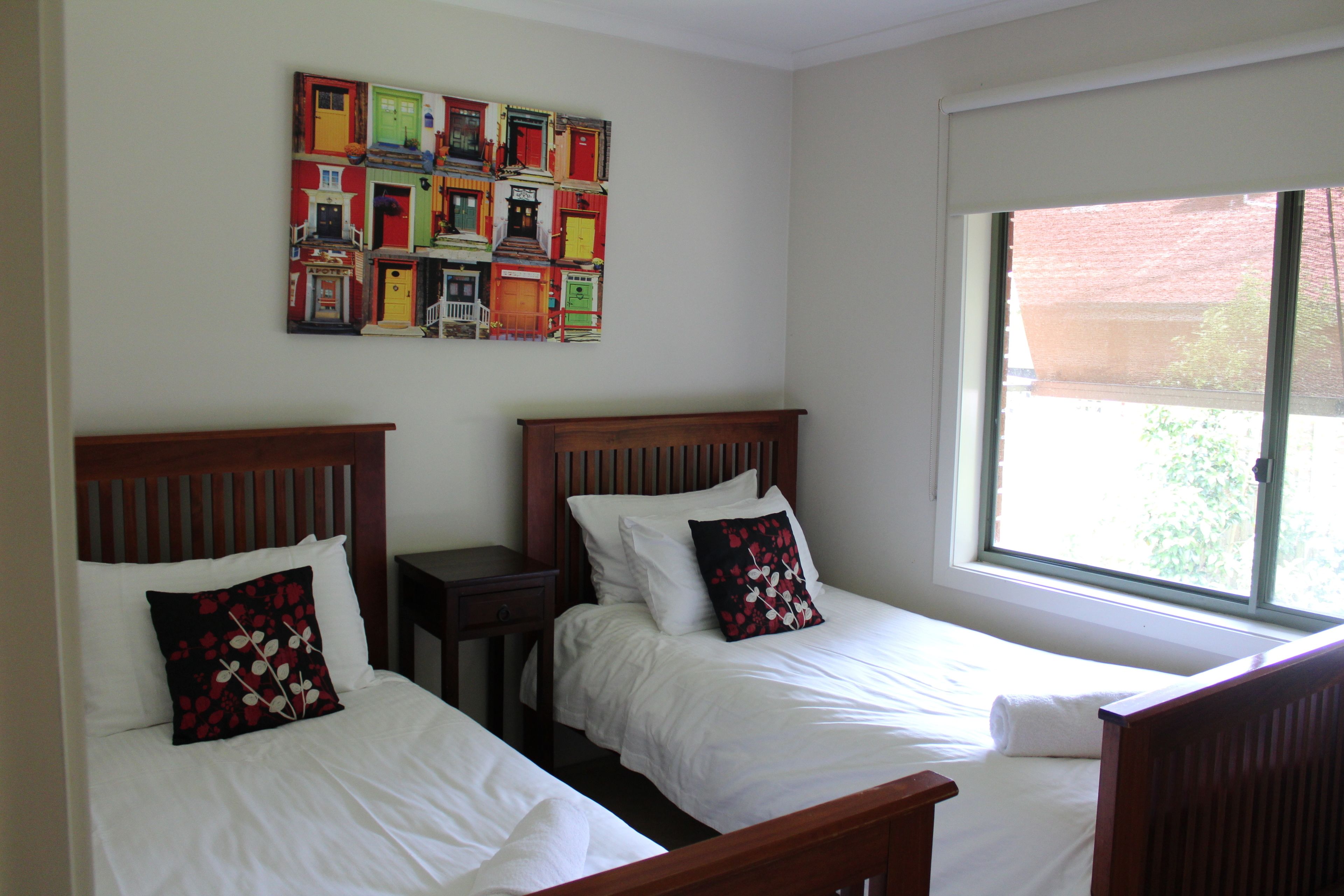 A hotel room with two beds, a nightstand, and a large window.