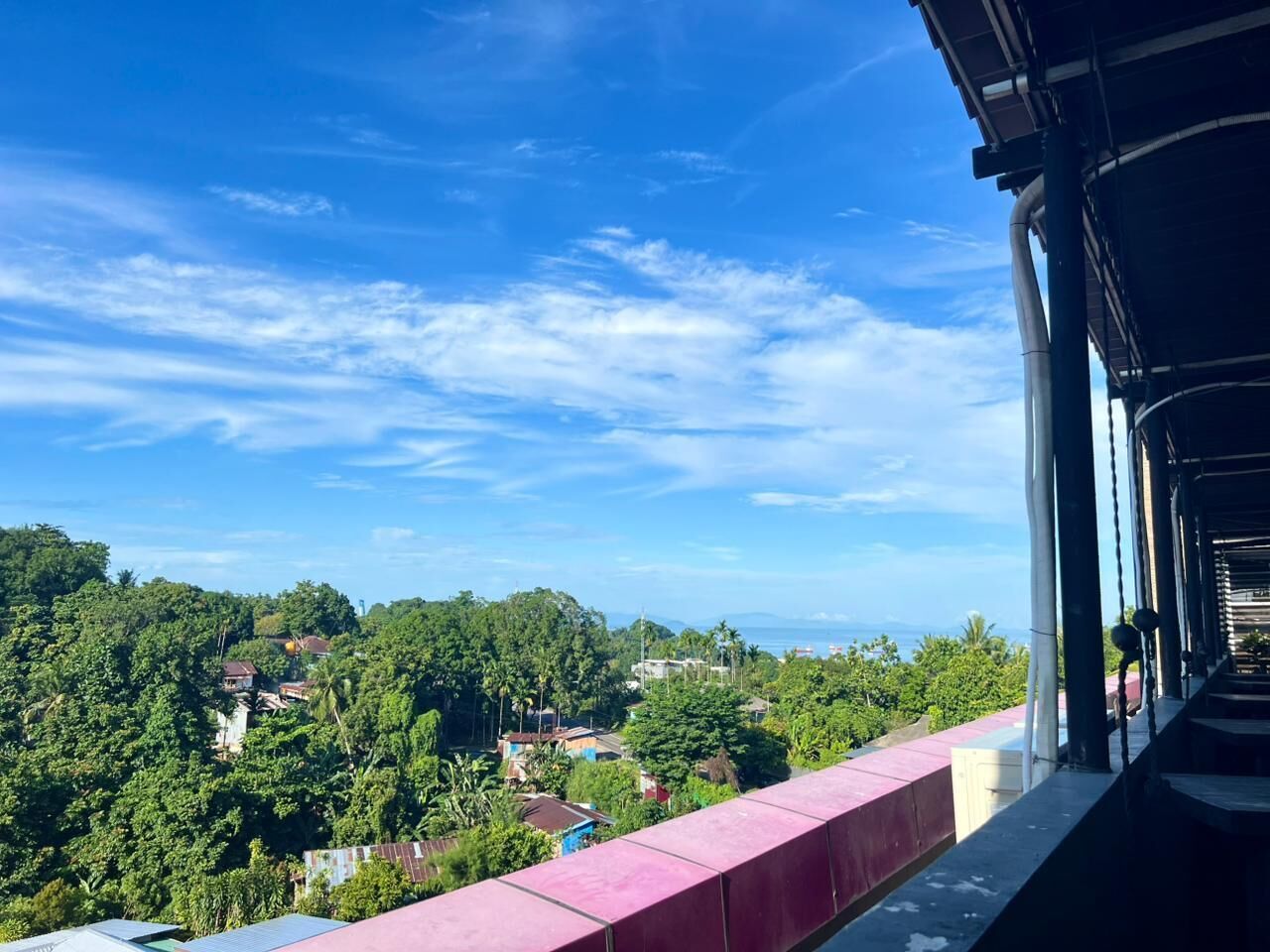 Un balcón con vistas a un paisaje verde y edificios.