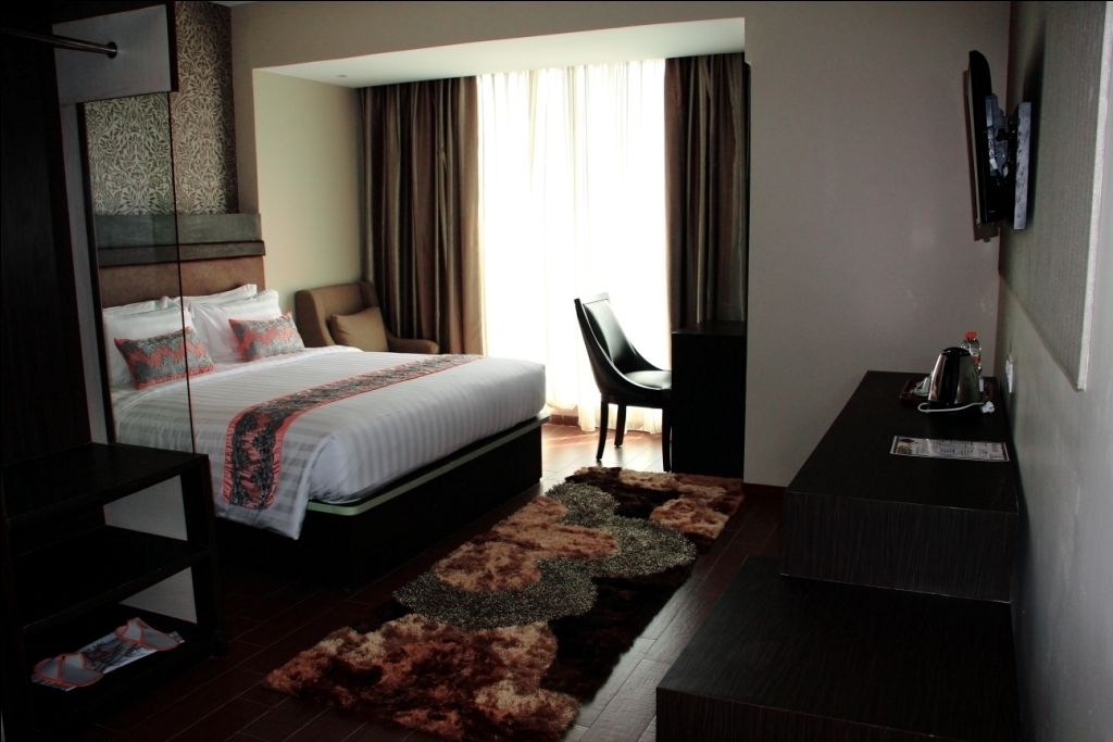 Una habitación de hotel moderna con una cama grande, un escritorio y una silla.