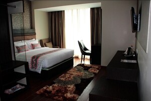 Una habitación de hotel moderna con una cama grande, un escritorio y una silla.