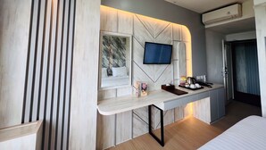 Ein modernes Hotelzimmer mit Bett, Schreibtisch, Flachbildfernseher, Minibar und Fenster.