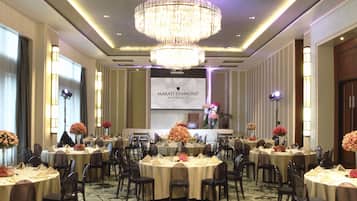 Un salón de banquetes con mesas redondas, sillas y una araña. Un cartel dice: "Makati Diamond Residences".