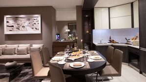 Un espace repas moderne avec une table ronde dressée pour six personnes, un canapé et une cuisine en arrière-plan.