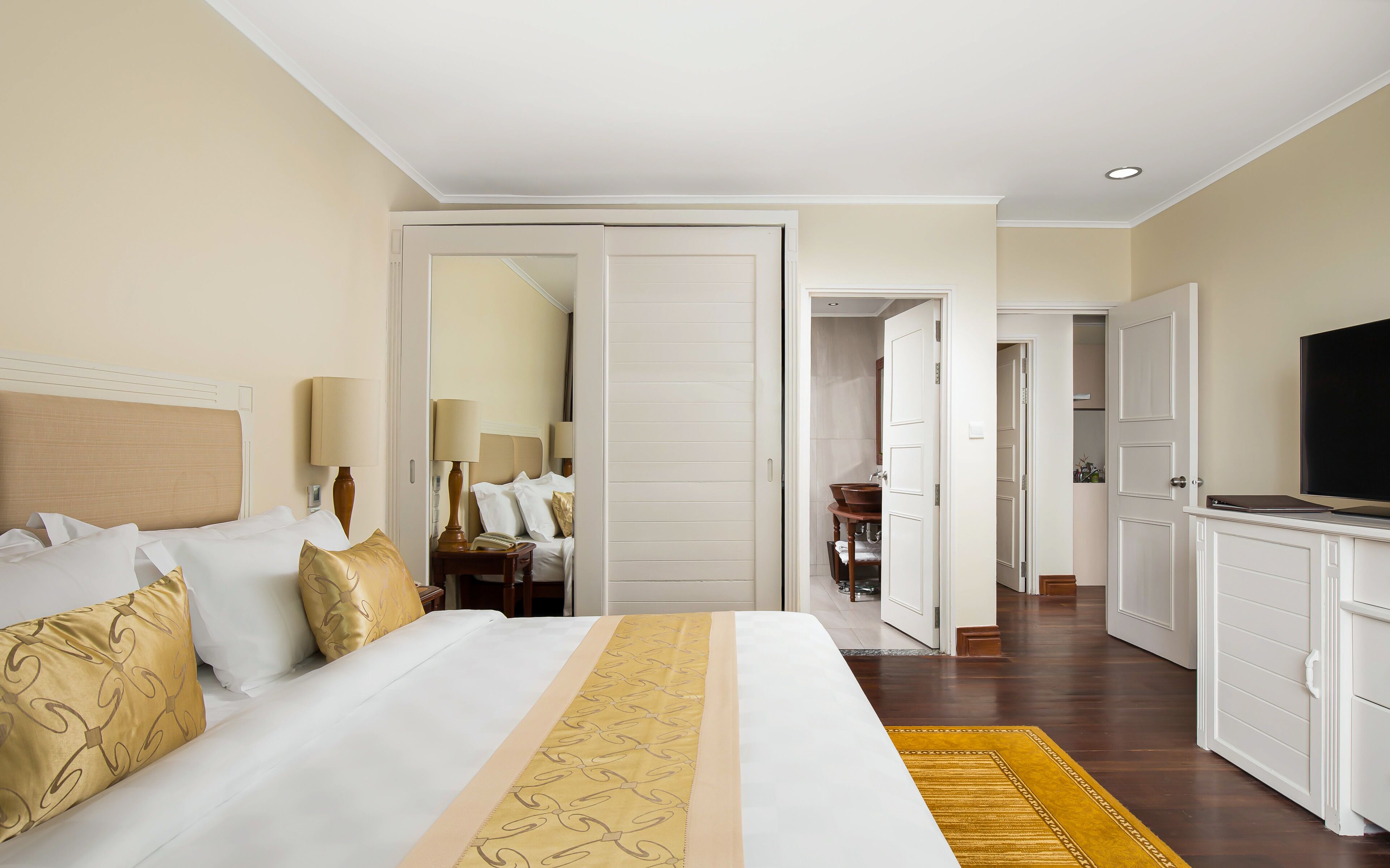 Een hotelkamer met een bed, nachtkastjes, een televisie en een badkamer zichtbaar door een open deur.